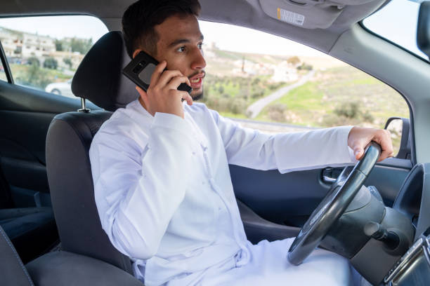 Man in traditional attire talking on the phone while driving.