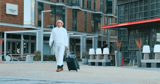 Person walking with suitcase in Elo 3 Damac Hills 2, featuring a mix of residential and commercial buildings.